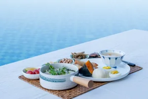A table setting featuring a variety of dishes served on ceramic plates near a swimming pool.
