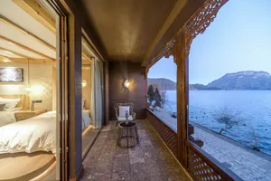 A cozy beach-front cabin suite featuring a relaxing outdoor patio overlooking serene waters and distant mountains, adorned wi