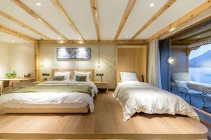 A modern hotel bedroom suite featuring a double bed and a single bed, with wooden flooring and walls, and a view of mountains