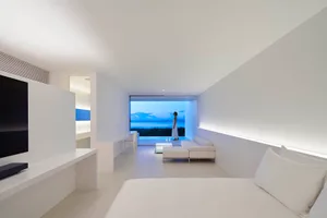 A minimalist residential interior with white plaster walls and a view of the sea.