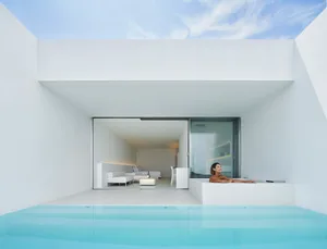 A minimalist pool area with glass walls and a white interior.