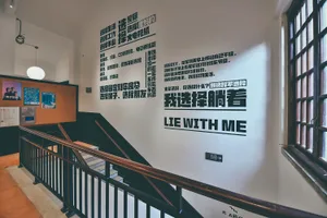 Text-based graphic design printed on a white wall with a staircase in the foreground, featuring various Chinese characters an