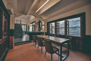 Interior view of a modern cafeteria with a wooden dining table, chairs, and open windows.