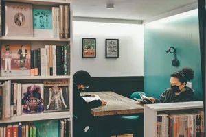 A study room with a wooden table surrounded by bookshelves filled with books.