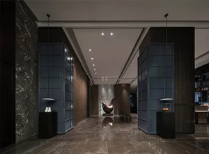 A modern minimalist lobby with a sleek metal chair, marble floor, and glass elements.