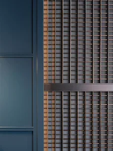A section of wall featuring a minimalist design with vertical metal bars and horizontal leather belts.