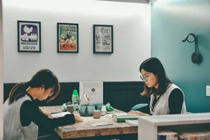 兩人在採光良好的書房空間內，坐在木質書桌前學習。