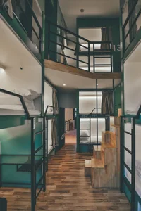 Industrial-style hostel room with steel and wooden furnishings and glass dividers.