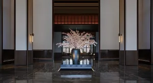 Modern hotel lobby with a marble floor and black vase with pink flowers.