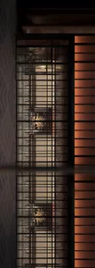 A close-up view of a metal grid window with a warm, inviting interior visible through the mesh.