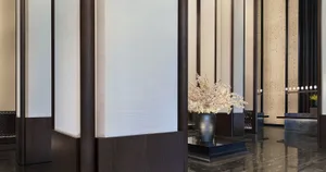 A minimalistic hotel lobby with wooden accents and a vase of flowers in the foreground.