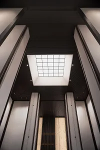 A sleek, modern hotel lobby featuring metallic columns and a skylight.