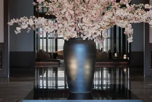 A large, modern lobby decorated with a glass vase filled with cherry blossoms.