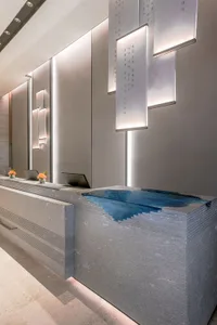 A minimalist reception desk made of concrete with a blue water feature.
