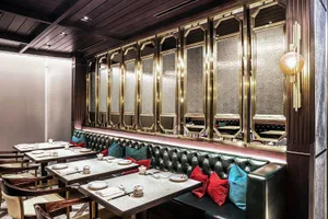 Table setting in a modern restaurant with leather seating, glass walls, metal accents, and wooden elements.