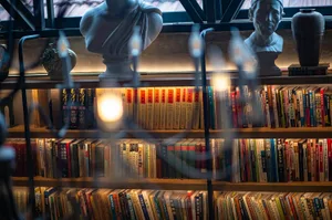 A library with wooden shelves filled with books, illuminated by warm lighting.