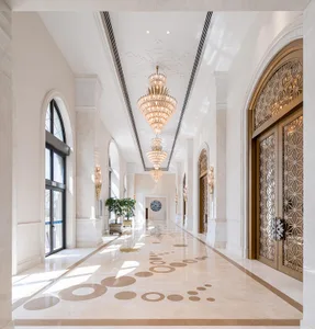 A luxurious hotel corridor with marble flooring, chandeliers, and ornate doors.