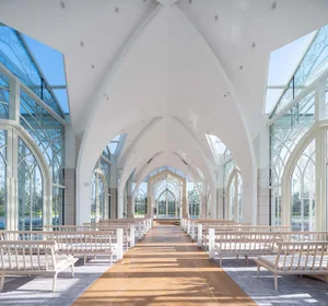 Modern church interior with glass walls, wooden benches, and concrete structural elements.