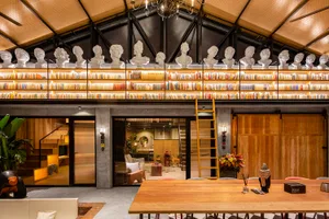 A modern library with concrete columns and wooden tables and shelves.