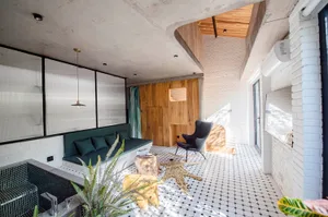A modern interior design with a living room featuring exposed concrete ceiling, brick walls, and tile flooring.