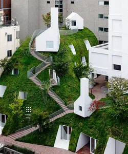 A minimalist urban building with green roofs and concrete pathways.