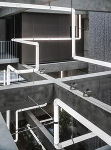 A modern industrial office space featuring exposed concrete pipes and minimalist design elements.
