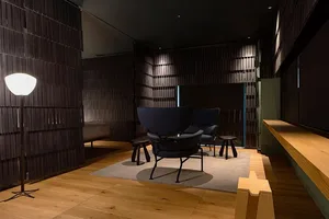 一間現代客廳，鋪設木質地板，配有黑色金屬框架扶手椅，以及深色木質牆面。