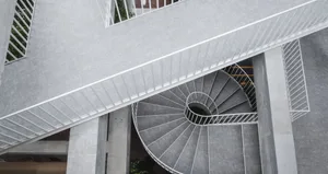 Concrete spiral staircase with white railings and a modern design.