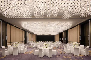 A modern banquet hall with white lighting and white tables and chairs.