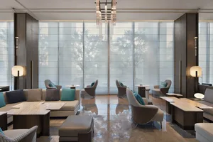 A modern hotel lobby with glass walls and metal furniture.