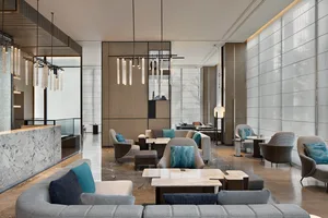 Modern, minimalist lobby featuring marble walls, glass elements, and wooden furniture.