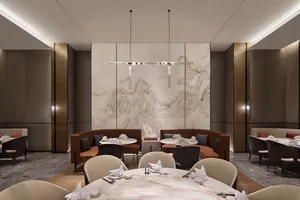 A modern restaurant interior featuring a large marble wall, round dining tables, and comfortable seating areas.