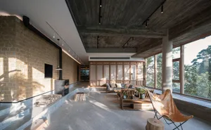 Industrial-style living room featuring concrete walls, a wood-burning stove, and large windows