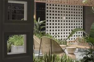 Outdoor seating area with wicker chairs, wooden stools, and greenery