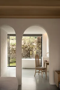 A minimalist bathroom with a white marble floor, walls, and bathtub.