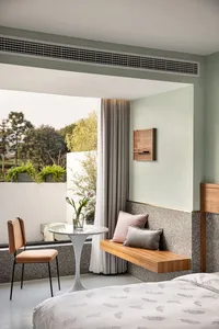 Minimalist bedroom featuring a concrete wall and wooden seating area.