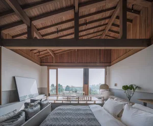A minimalist bedroom featuring wooden furniture and a large window overlooking nature.