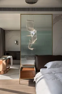 A modern bedroom featuring marble walls, a copper bathtub, leather headboard, and walnut nightstand.