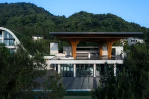 A modern architectural building featuring a wooden facade, concrete base, and glass roof.