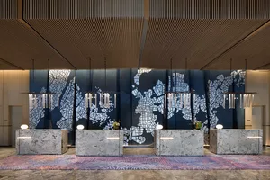 A modern hotel lobby reception area featuring marble countertops, patterned tiles, and illuminated lighting fixtures.
