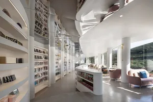 現代圖書館室內，白色混凝土書架與玻璃牆面。