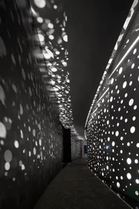 A corridor with modern lighting featuring metal perforated panels.