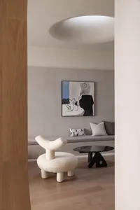 A modern living room with white furniture, featuring a round white chair, a black coffee table, and a comfortable seating are