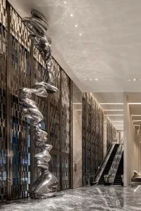 A modern lobby featuring a metal sculpture as a centerpiece, with a sleek, gray floor and tall walls.