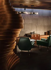 A modern lounge with green leather chairs, wooden tables, and striped leather walls