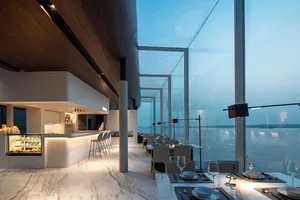 Modern restaurant interior featuring marble and glass elements with a view of the water.