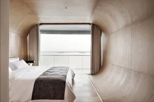 Modern minimalist bedroom featuring wood interiors and a view of the ocean.