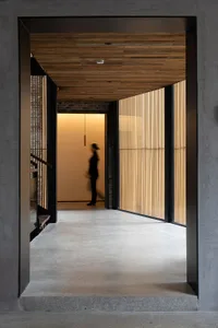 Modern minimalist interior space featuring wood-paneled walls and concrete flooring.