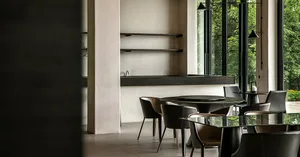 A modern dining room with glass tables and matte-finished chairs, featuring a minimalist design and a sleek, contemporary aes