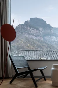 A modern interior with a red circular object on a wooden floor and a mountain view outside the window.